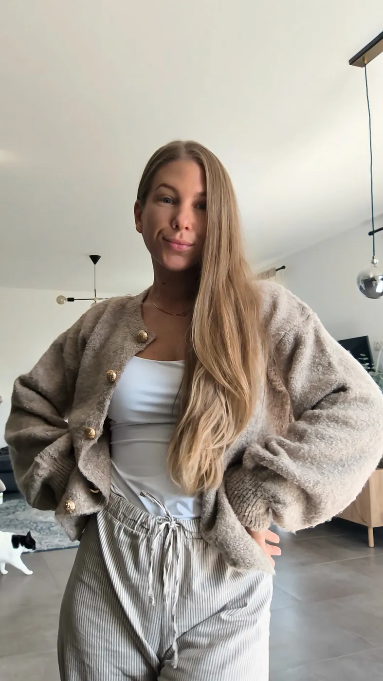 Helen Fritzsche steht lächelnd in ihrem Wohnzimmer, die Hände in den Hüften